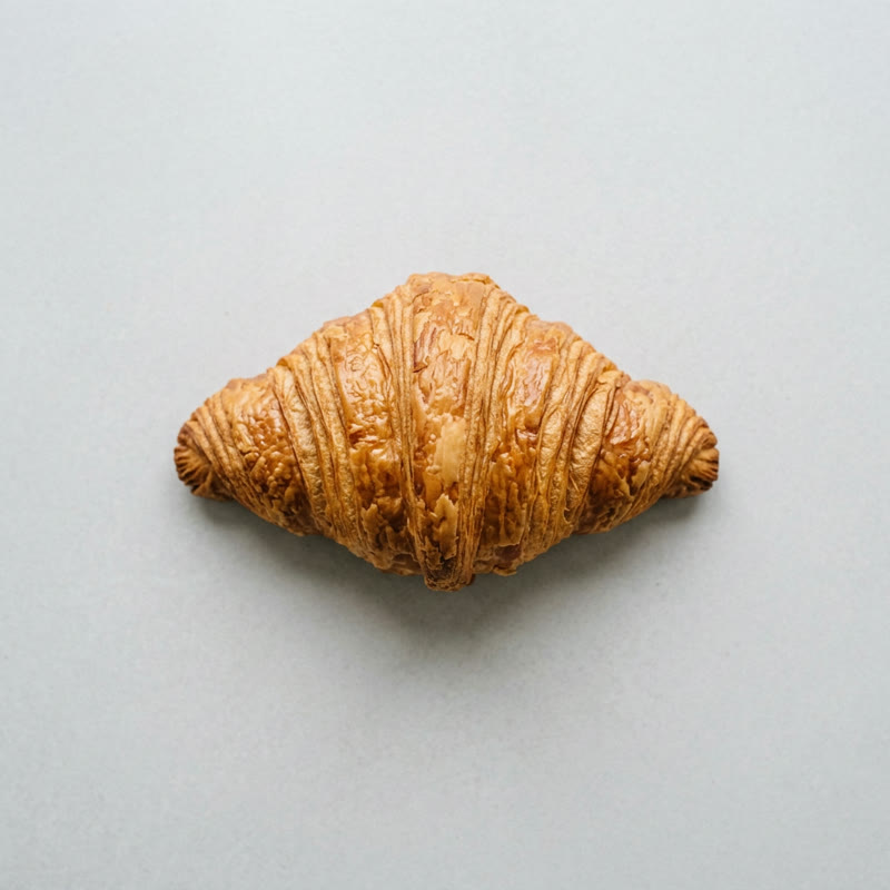 A golden croissant on a light grey background