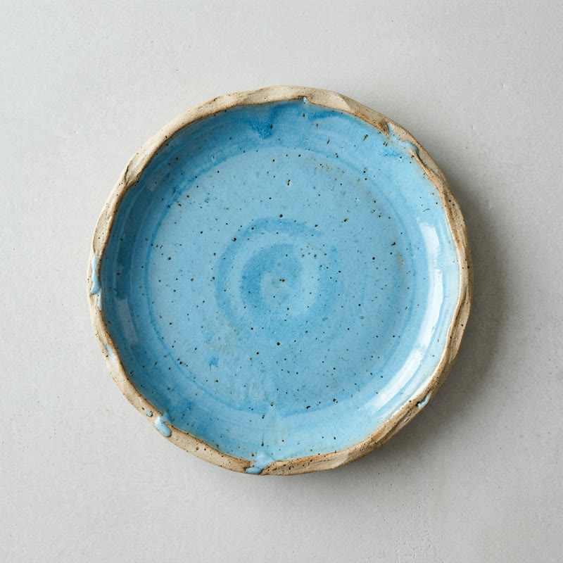A sky-blue hand-thrown ceramic plate on a light grey background