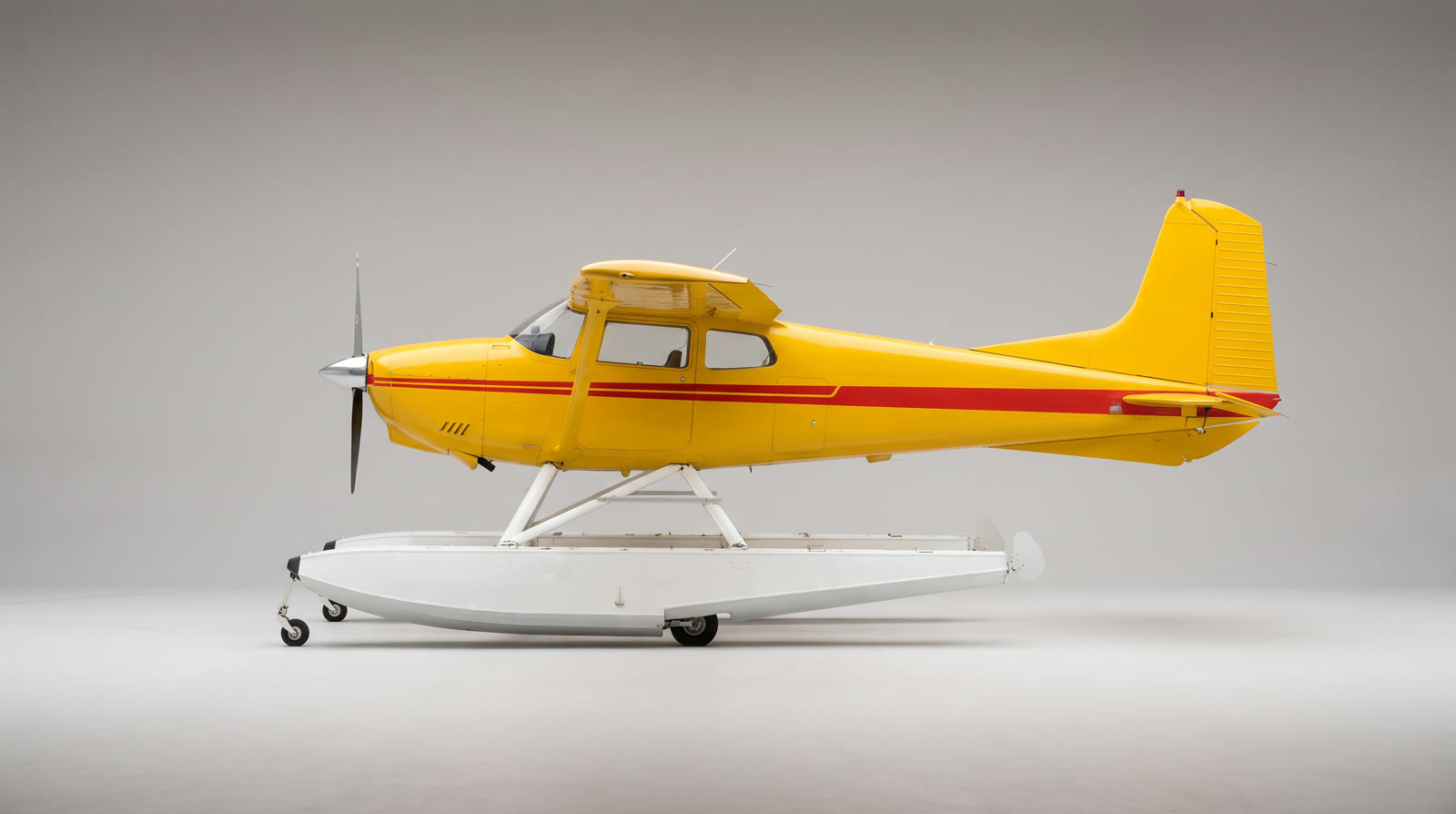 A yellow seaplane with a red stripe and white floats on a plain gray background